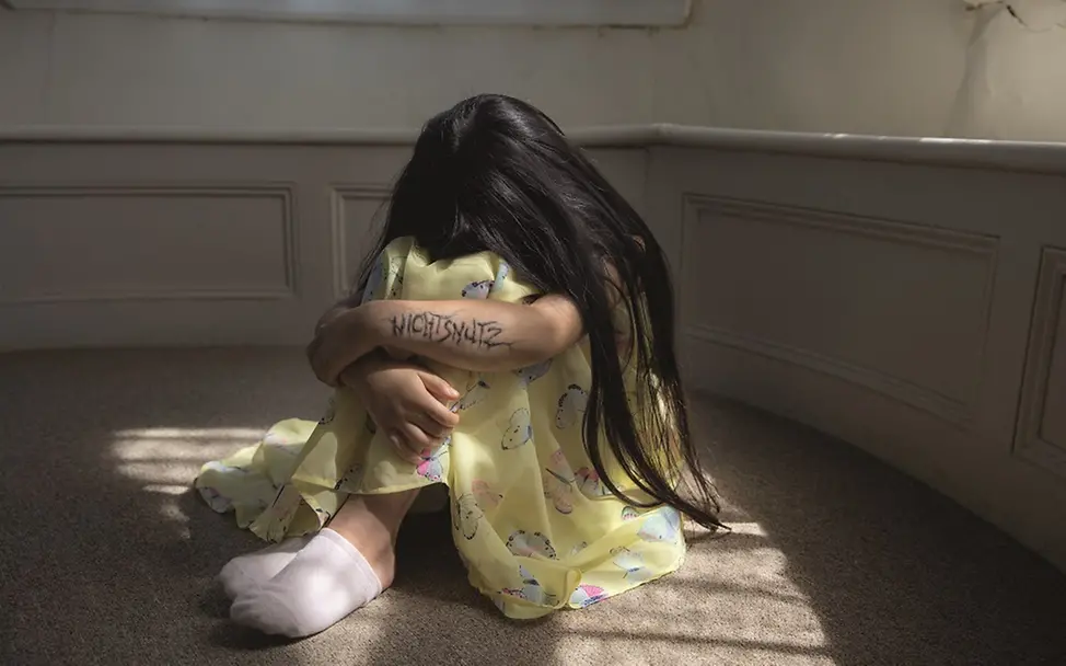 Ein Mädchen vergräbt den Kopf zwischen Armen und Beinen. | © UNICEF/Madeline Kelly Ein Mädchen vergräbt den Kopf zwischen Armen und Beinen.