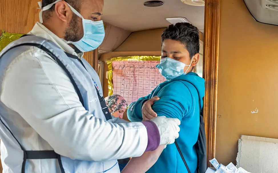 Ein Junge in Ägypten lässt sich von einem Gesundheitshelfer impfen. | © UNICEF/Ragaa Mobiles Gesundheitsteam: UNICEF schickt mit Impfbussen Gesundheitshelfer*innen in entlegene Gebiete und impft Kinder.