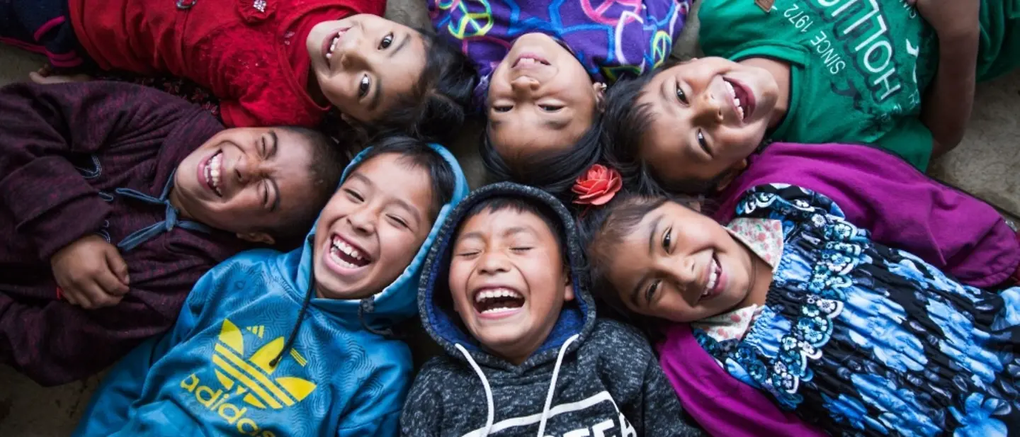 Kinderrechte sind grundlegende Rechte, die allen Kindern zustehen | © UNICEF/Willocq Sieben Kinder liegen zusammen in einem Kreis und lachen.