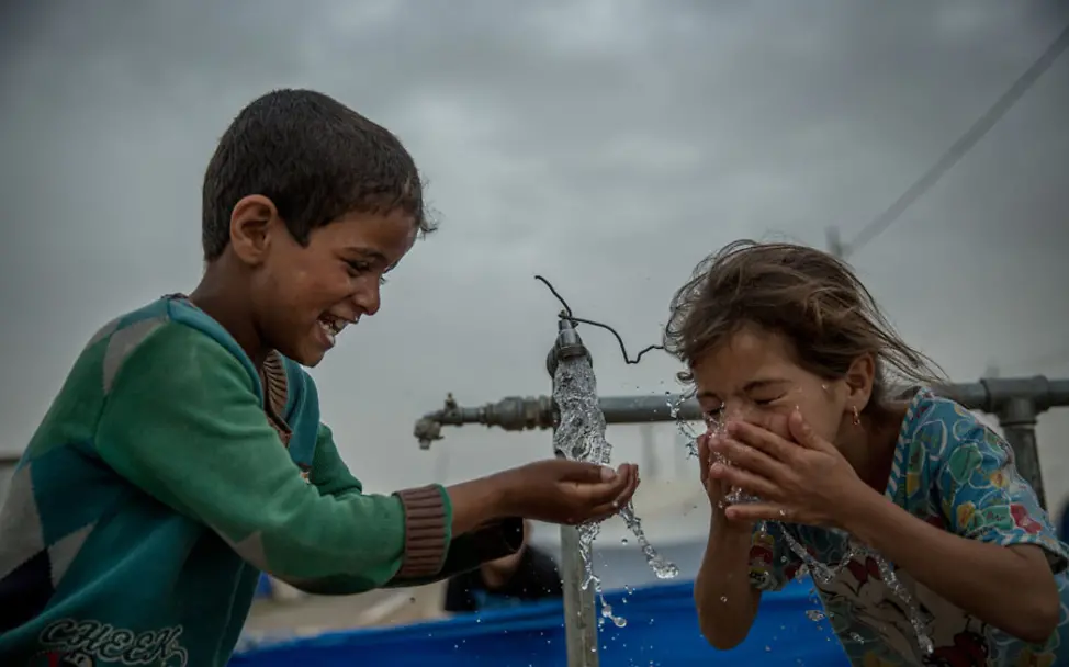 Zahraa und Mahmood trinken sauberes Wasser aus einem UNICEF-Wassertank | © UNICEF Irak/Anmar Irak: Zwei Kinder trinken sauberes Wasser aus einem Wassertank