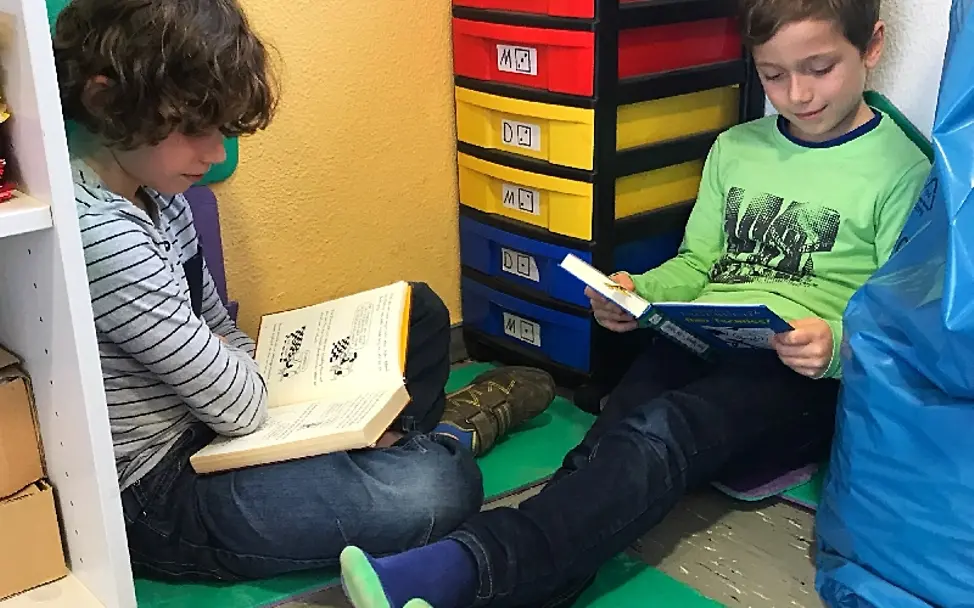 Diese zwei Jungs haben sich eine Leseecke eingerichtet | © UNICEF/Ursula Grass Lesen für UNICEF: Zwei Jungs haben es sich in einer Ecke gemütlich gemacht