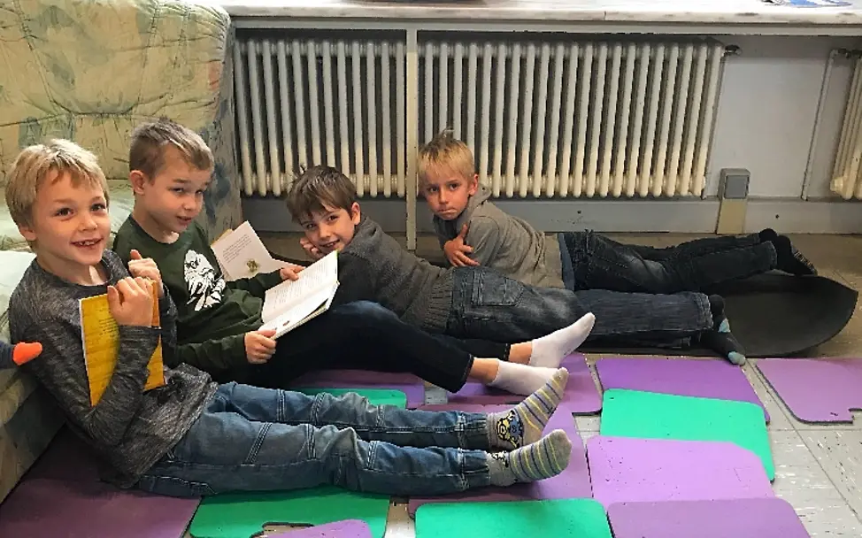 Zu Viert liest es sich gleich viel besser | © UNICEF/Ursula Grass Lesen für UNICEF: Hier haben es sich vier Jungs auf den Matten bequem gemacht