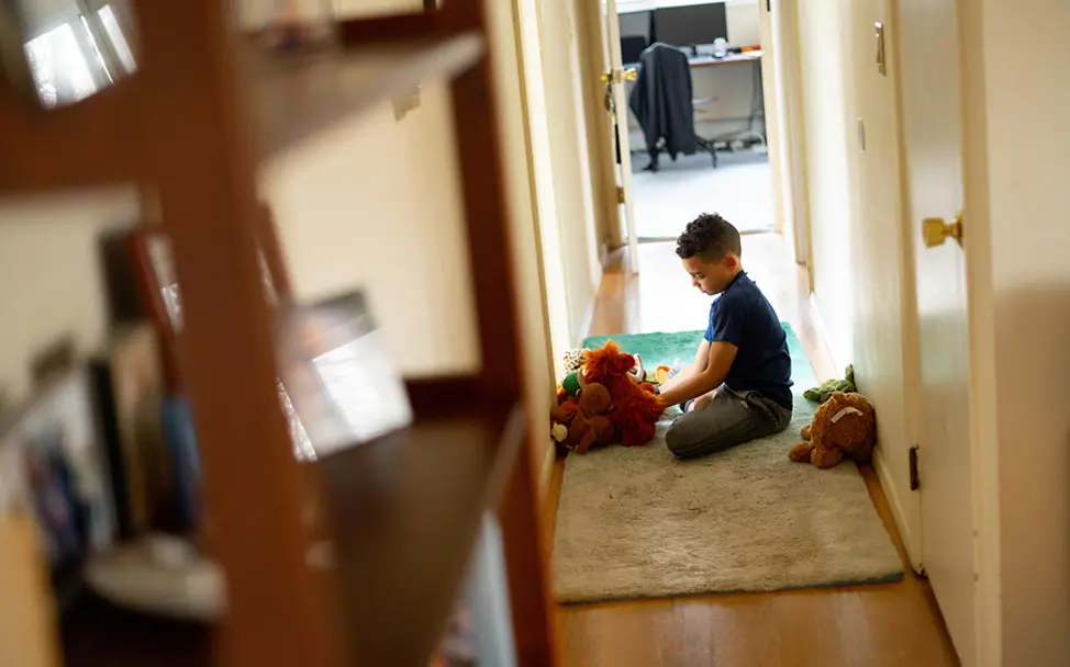 Ein Junge spielt im Flur mit seinen Kuscheltieren. | © UNICEF/McIlwaine Kinderschutz: Junge spielt mit seinen Kuscheltieren.