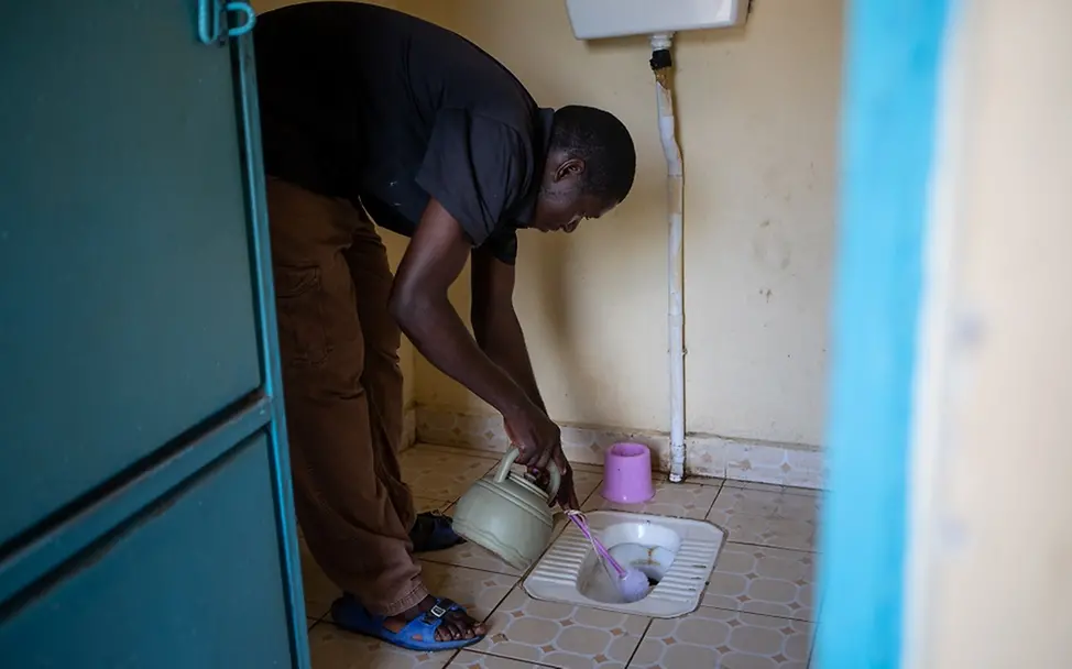 Michael Dao reinigt die sanitäre Anlage von UNICEF. | © UNICEF/de la Guardia Südsudan: Ein Mann säubert die sanitäre Anlage.