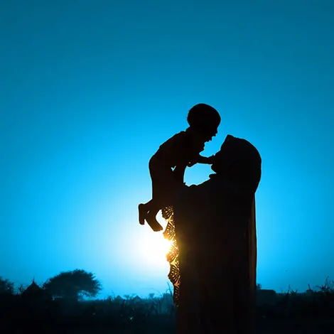 75 Jahre UNICEF: Das UNICEF-Logo hat sich über diesen Zeitraum kontinuierlich weiterentwickelt. | © UNICEF/Sang Mooh Eine Mutter in einem afrikanischen Dorf hält ihr Kleinkind über sich in den Himmel.