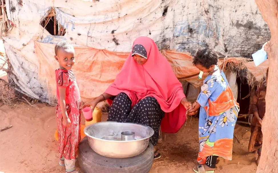 Klimawandel: So sprechen Sie mit Kindern darüber. | © UNICEF/Taxta Klimawandel für Kinder erklärt: Eine Frau mit zwei Kindern vor einer Schüssel mit Wasser.