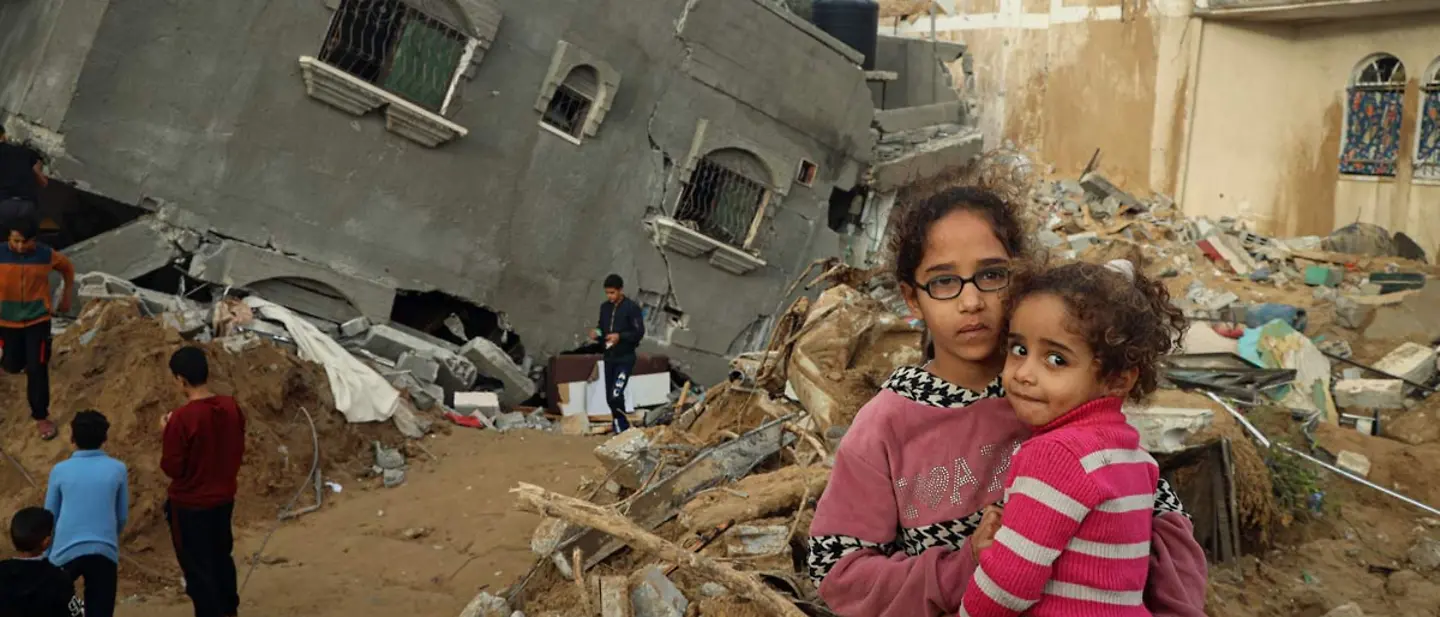 Abeer hält ihre 4-jährige Schwester Zahra vor ihrem zerstörten Haus in Rafah | © UNICEF/El Baba Spenden für Gaza: Die 12-jährige Abeer hält ihre 4-jährige Schwester Zahra vor ihrem zerstörten Haus in Rafah