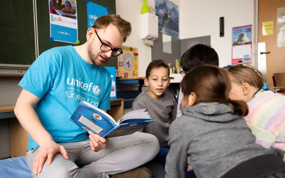 UNICEF Gruppen in Ihrer Nähe unterstützen die Schulaktion | © UNICEF/Etges Ehrenamtlich Engagierter liest gemeinsam mit den Schulkindern.