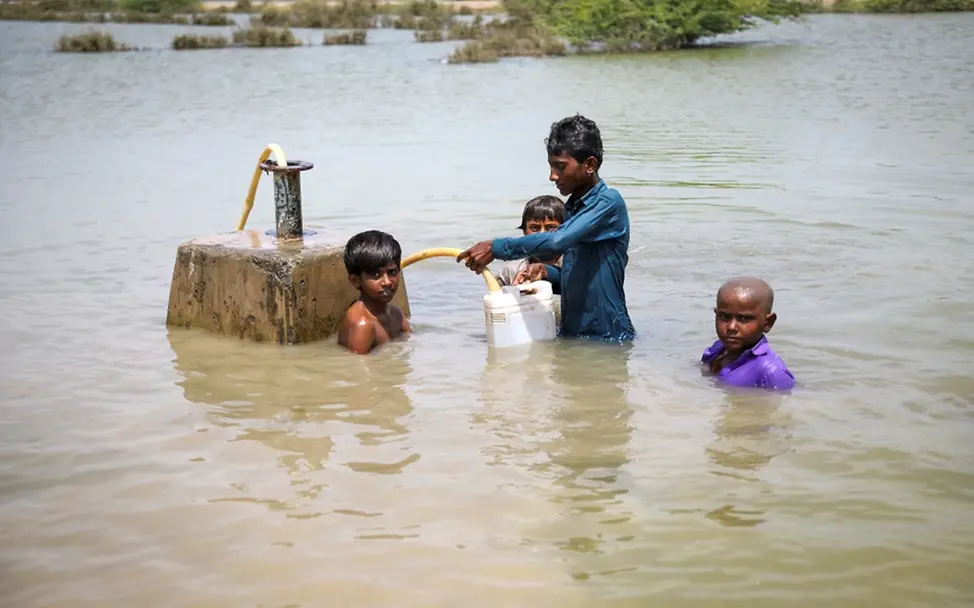 Kinder versuchen Trinkwasser aus einer überfluteten Wasserpumpe zu retten. | © UNICEF/UN0701707/Zaidi Hochwasser folgen: Kinder versuchen Trinkwasser aus einer überfluteten Wasserpumpe zu retten.