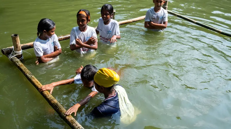 In einem geschützten Bereich zeigt Mim den Kindern erste Schwimmübungen. | © UNICEF/UNI487210/Himu In einem geschützten Bereich zeigt Mim den Kindern erste Schwimmübungen.