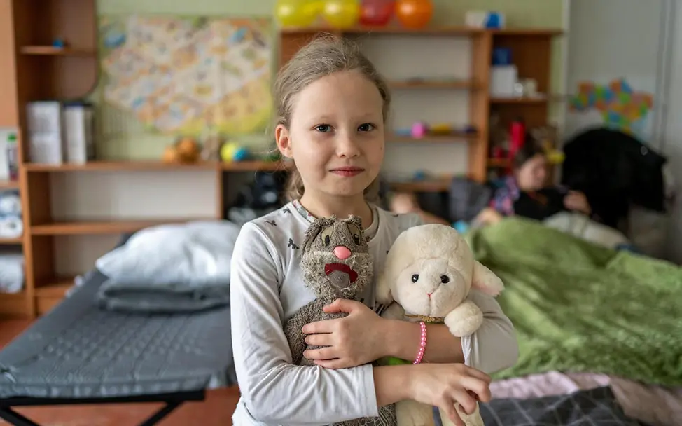 Ein geflüchtetes ukrainisches Mädchen mit ihren Stofftieren in einer Notunterkunft | © UNICEF/Filippov Ukraine Spenden: Menschen wie dieses Mädchen brauchen im Krieg dringend Nothilfe von Hilfsorganisationen wie UNICEF.
