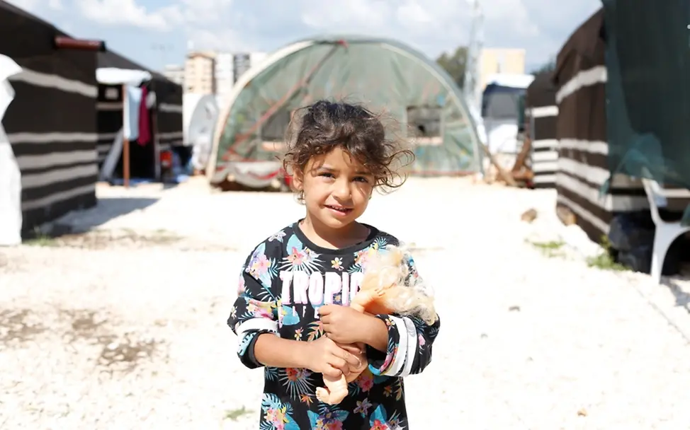 Ein kleines Mädchen hält sein Spielzeug in einer Notunterkunft in Hatay, Türkei, nachdem der Südosten der Türkei am 1. Mai 2023 von zwei verheerenden Erdbeben erschüttert wurde. | © UNICEF/UN0835808/Kiliç Weltflüchtlingstag: Ein Mädchen hält sein Spielzeug in einer Notunterkunft in Hatay, Türkei, nach zwei verheerenden Erdbeben.