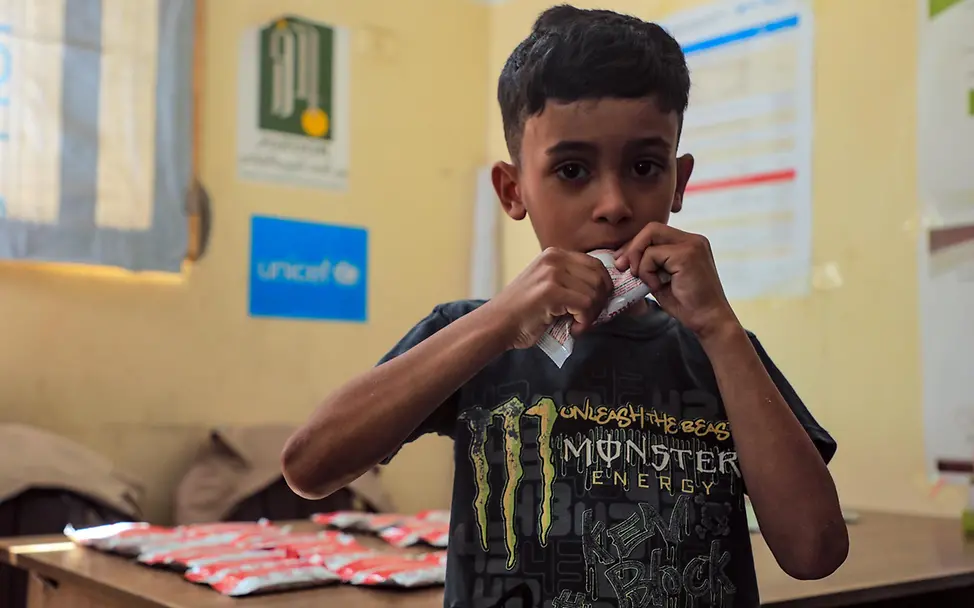 Ein stark unterernährter Junge isst ein Päckchen Erdnusspaste gegen den Hunger | © UNICEF/Nateel Gaza spenden: Die Hungersnot bringt die Kinder im Gazastreifen in tödliche Gefahr.