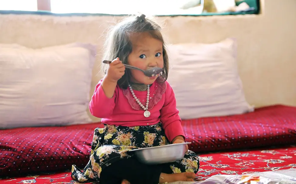 Ein Mädchen in Afghanistan isst Reis und Gemüse aus einer Schüssel. | © UNICEF/UNI827358/ Kinderarmut spenden: Ein Mädchen in Afghanistan isst Reis und Gemüse aus einer Schüssel.