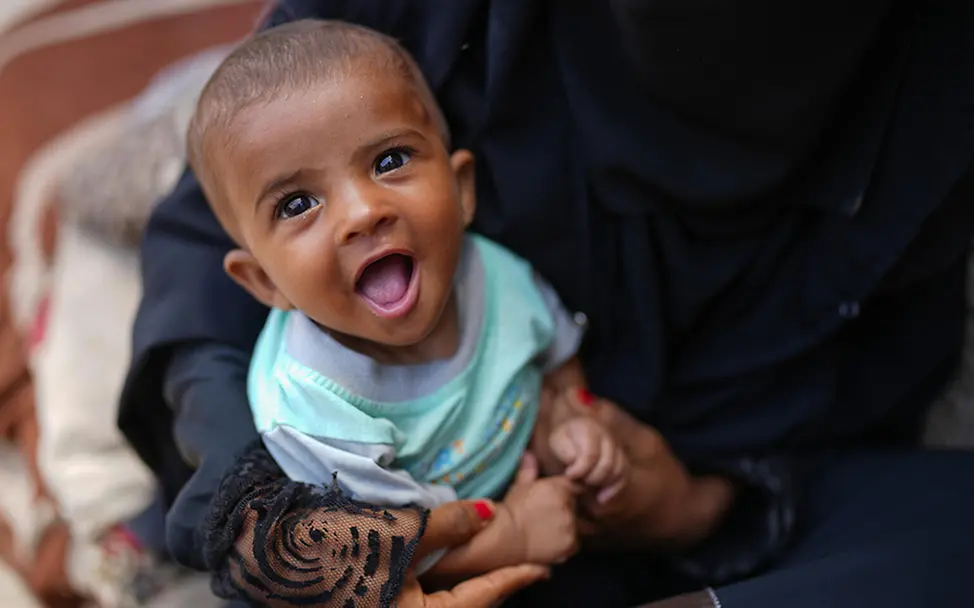 Jemen: Baby lacht im Schoß der Mutter. | © UNICEF/Alaa Noman Jemen: Baby lacht im Schoß der Mutter.