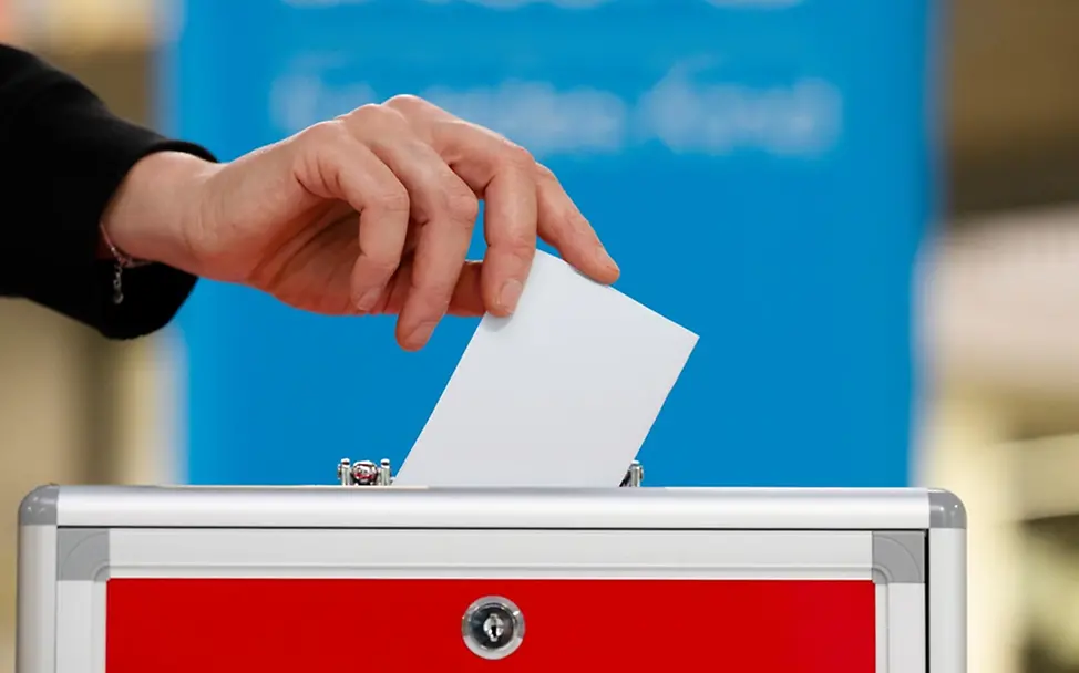 Ein Wahlzettel wird in die Wahlurne geworfen. | © UNICEF/Etges Was ist Demokratie einfach erklärt: Ein Wahlzettel wird in die Wahlurne geworfen.