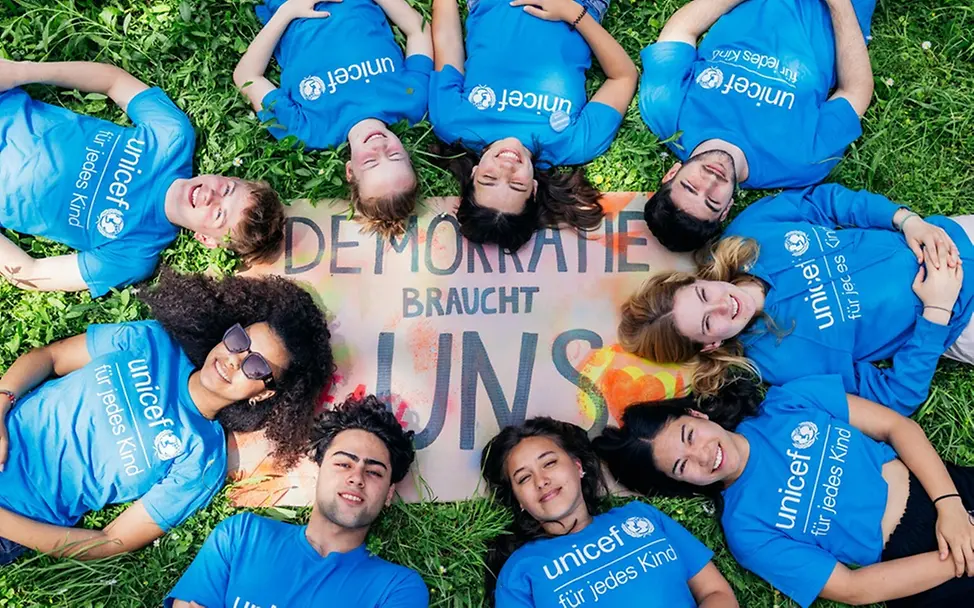 Jugendliche vor einem Schild zum Thema Demokratie. | © UNICEF/Stroisch Was ist Demokratie einfach erklärt: Jugendliche vor einem Schild zum Thema Demokratie