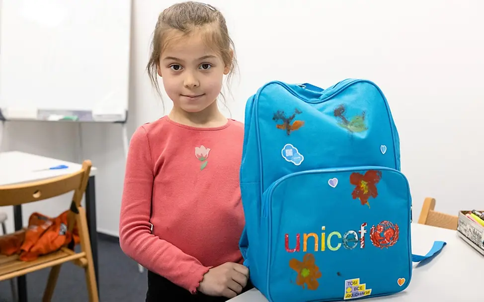 Olha (7) zeigt stolz ihren blauen UNICEF-Schulrucksack. | © UNICEF/Figula Gute Nachricht: Olha (7) zeigt stolz ihren blauen UNICEF-Schulrucksack.