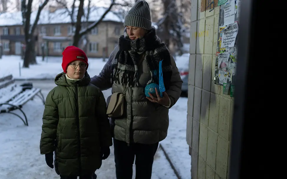 Winter in der Ukraine: Ein Junge steht in Kiew mit seiner Mutter in einem Hauseingang | © UNICEF/Filippov Ukraine Krieg: Der Winter bringt die Kinder zusätzlich in Gefahr