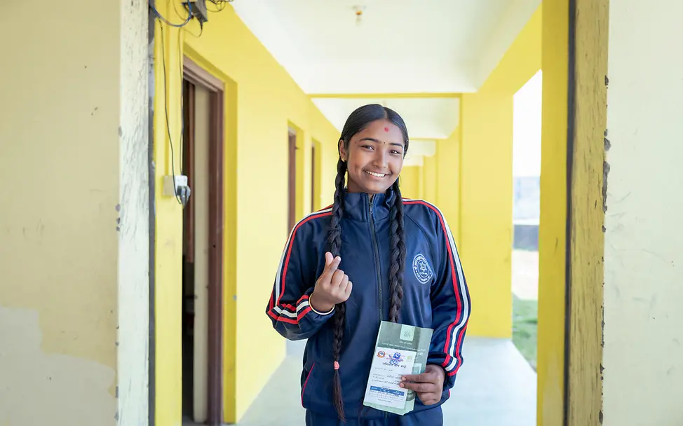 Manisha strahlt glücklich, weil sie mit allen wichtigen Impfungen versorgt ist. | © UNICEF/Upadhayay Gute Nachricht aus Nepal: Manisha hält ihre Impfkarte in der Hand und lacht.