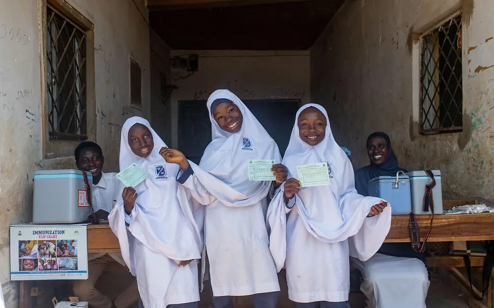 Drei Schülerinnen nach ihrer Schutzimpfung in der Schule. | © UNICEF/Moses Gute Nachrichten aus Nigeria: Drei Mädchen stehen in ihrer Schule und lächeln nach Erhalt einer Impfung.