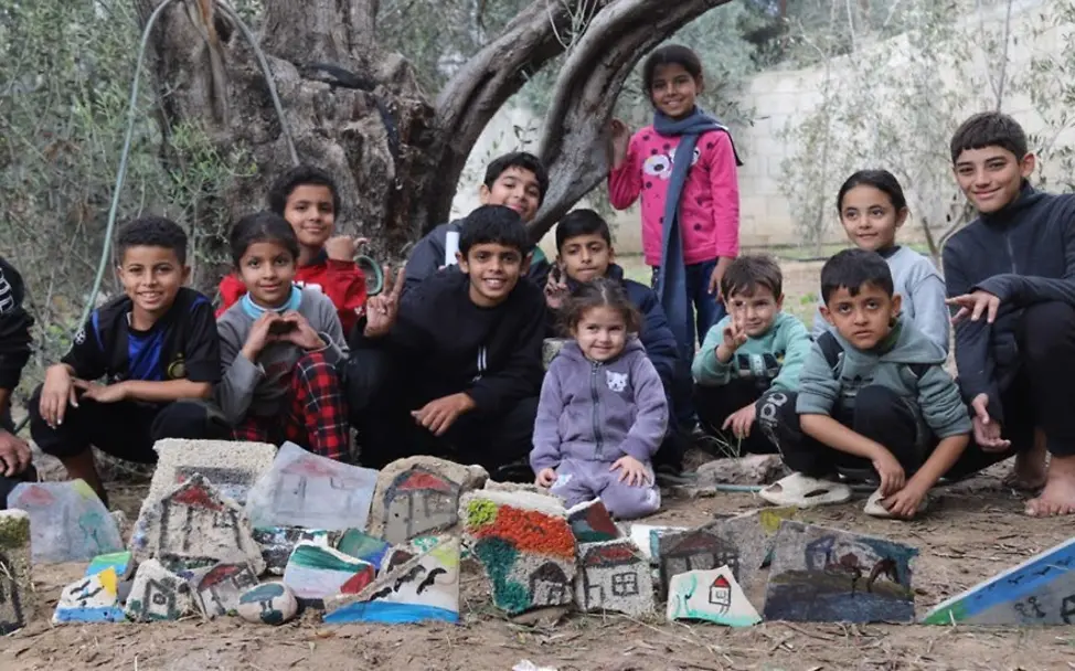 Zeichnungen auf Trümmerteilen. © UNICEF-SOP/2025 Kinder knien vor ihren Kunstwerken
