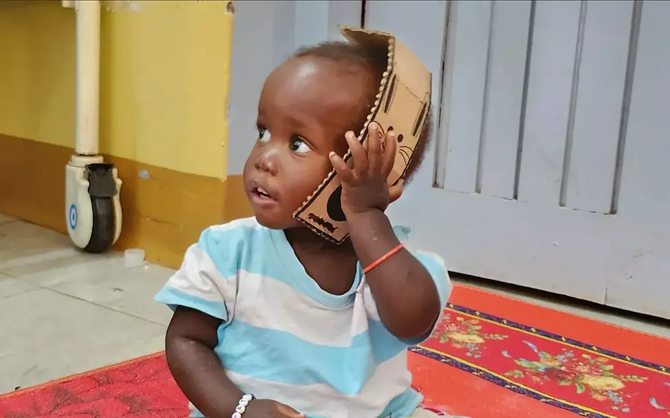 Nachhaltigkeit trifft Innovation für Kinder. | © UNICEF Project Play: Ein Kleinkind spielt mit einem Pappspielzeug