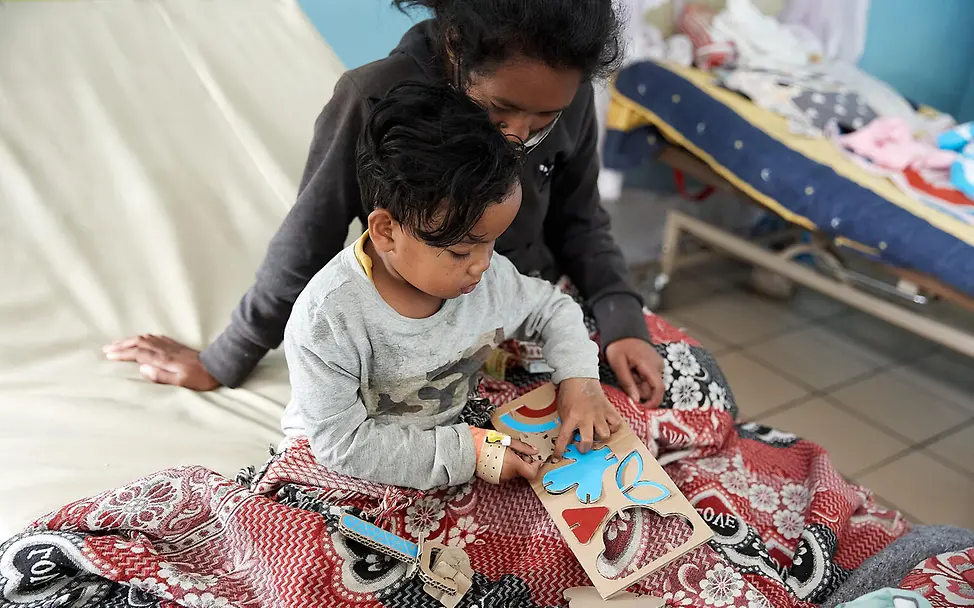 Kind und Mutter freuen sich an den mitgelieferten Spielsachen. | © UNICEF/Andriantsoarana Project Play: Im Gesundheitszentrum wird das Spielzeug aus Pappe genutzt.
