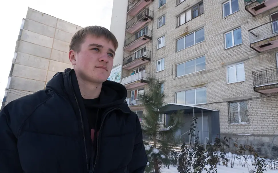 Ein Jugendlicher in Charkiw vor einem Hochhaus. | © UNICEF/Filippov Ukraine Krieg: Ein Jugendlicher in Charkiw vor einem großen Wohnhaus.