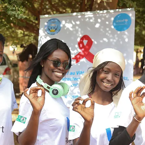 Aids einfach erklärt: UNICEF unterstützt weltweit Jugendliche, die sich zu wichtigen Themen wie HIV austauschen. | © UNICEF/Keïta AIDS einfach erklärt: Vier Engagierte für U-Report posieren vor einem Plakat.