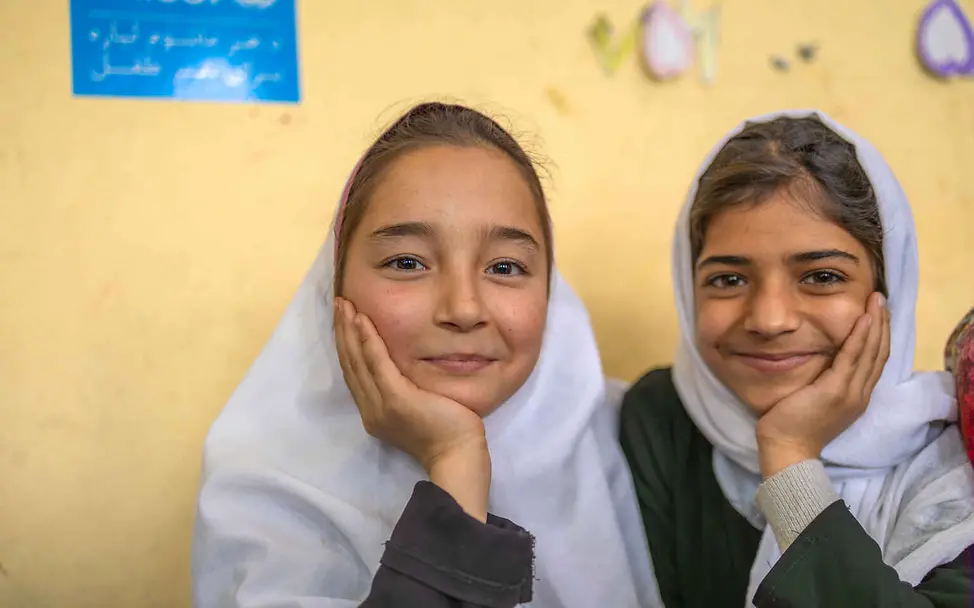 UNICEF setzt sich weltweit für Schulen und geschützte Räume für Kinder ein | © UNICEF/Khayyam Recht auf gewaltfreie Erziehung: Zwei Mädchen blicken lächelnd in die Kamera..