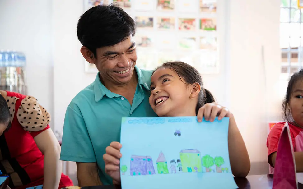 UNICEF unterstützt den Aufbau lokaler Elterngruppen, in denen sich Eltern austauschen und beraten lassen können | © UNICEF/Vu Le Hoang Recht auf gewaltfreie Erziehung: Ein Vater lächelt seine Tochter auf seinem Schoß an.