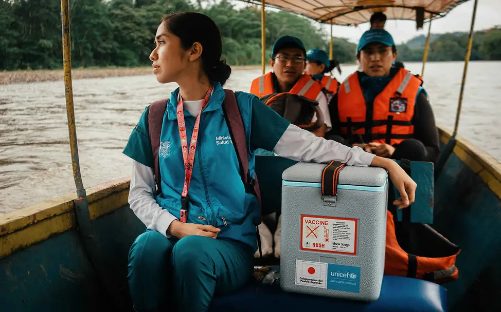 Solarbetriebene Kühlschränke und Kühlbehälter helfen, Impfstoffe sicher zu lagern | © UNICEF/Vallejo Prut Warum impfen: Eine Gesundheitshelferin transportiert eine Kühlbox mit Impfstoffen per Boot.