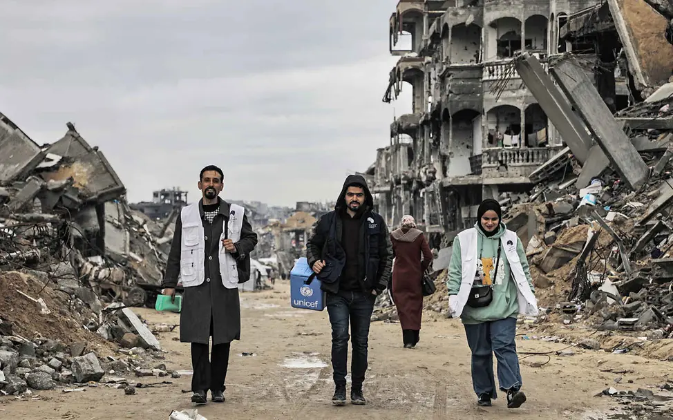 Auch in schwer erreichbaren Gebieten sind die UNICEF-Helfer*innen vor Ort, um Kinder zu impfen. | © UNICEF/Nateel Warum impfen: UNICEF-Gesundheitshelfer*innen laufen durch eine zerstörte Straße in Gaza.