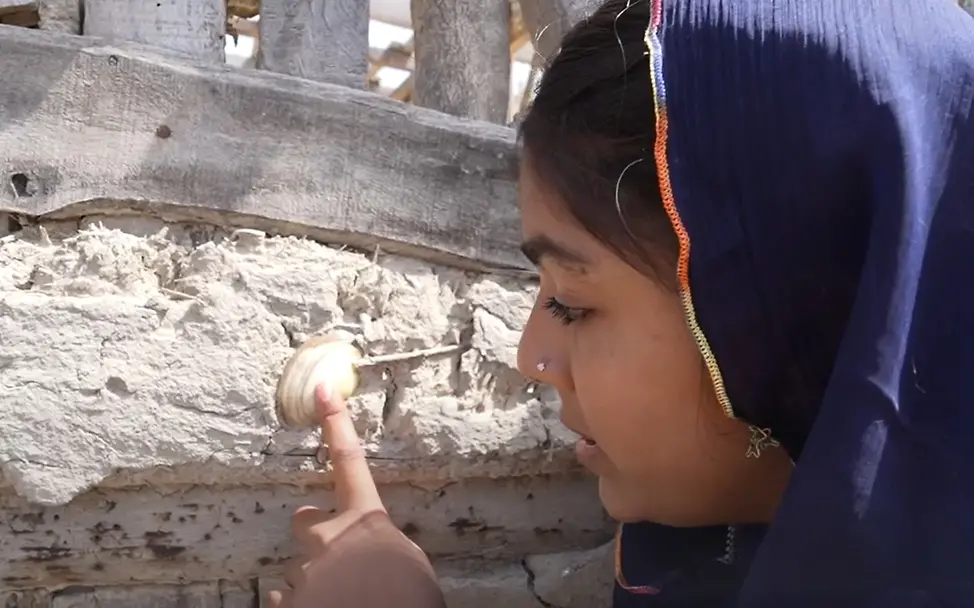 Sobh zeigt auf eine Muschel in der Hauswand. | © UNICEF Gute Nachrichten: Sobh aus Pakistan