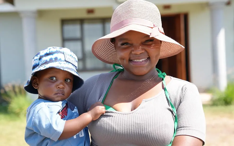 Lethokuhle und ihr Sohn Kusaselihle stehen vor ihrem Haus in KwaZulu-Natal in Südafrika. | © UNICEF/Mkhize Kindererziehung Tipps: Lethokuhle und ihr Sohn Kusaselihle stehen vor ihrem Haus in KwaZulu-Natal in Südafrika.