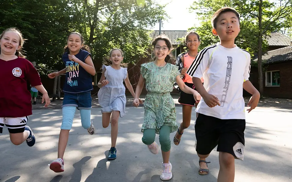 Grundgesetz einfach erklärt: Jeder Mensch ist nach dem Grundgesetz frei und darf sein Leben frei gestalten | © UNICEF Grundgesetz einfach erklärt: Kinder auf einem Schulhof laufen lachend auf die Kamera zu.