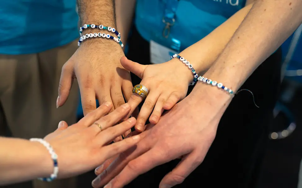 Grundgesetz einfach erklärt: Kein Mensch soll besser oder schlechter behandelt werden als andere. | © UNICEF/Sachse-Grimm Grundgesetz einfach erklärt: Vier Hände mit Namens-Armbändern berühren sich.
