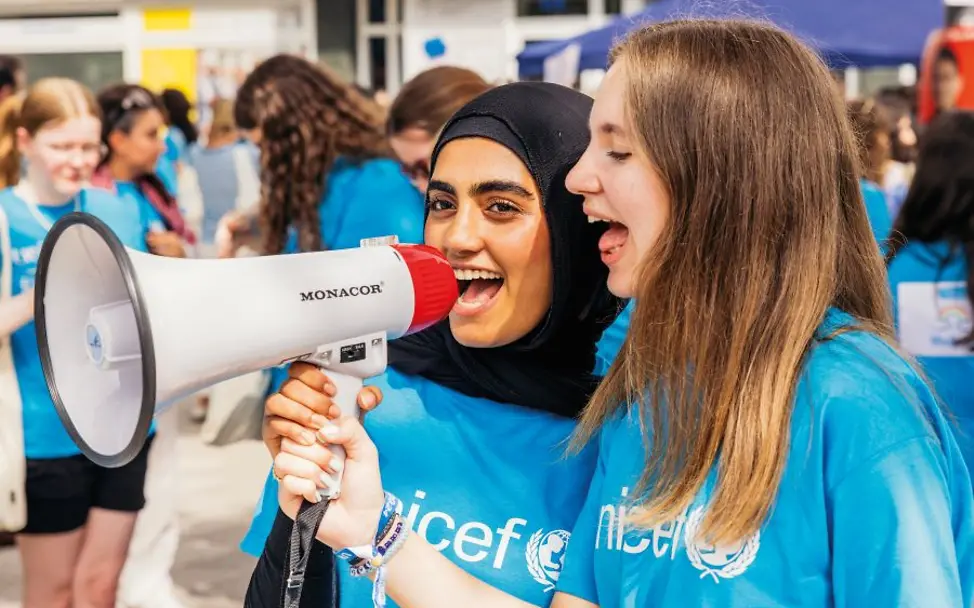 Kinderfreundliche Kommunen: Jugendliche mit UNICEF-Shirt und Megafon. | © UNICEF/Stroisch Jugendliche in UNICEF-T-Shirts nutzen ein Megafon bei einem Event draussen.
