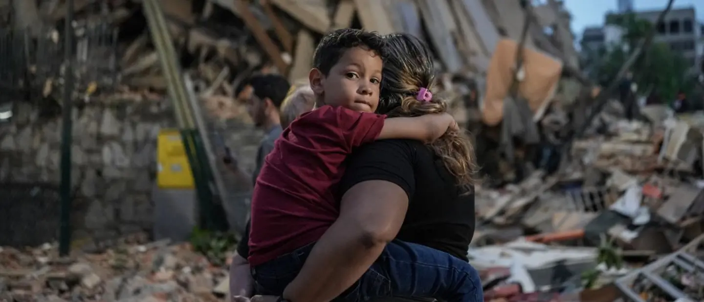 Erdbeben haben verheerende Folgen für Menschen in Venezuela verursacht. | © UNICEF/QUINTERO/AFP Erdbeben Venezuela spenden: Eine Mutter mit ihrem Kind inmitten von Trümmern. Kinder brauchen dringend Hilfe.