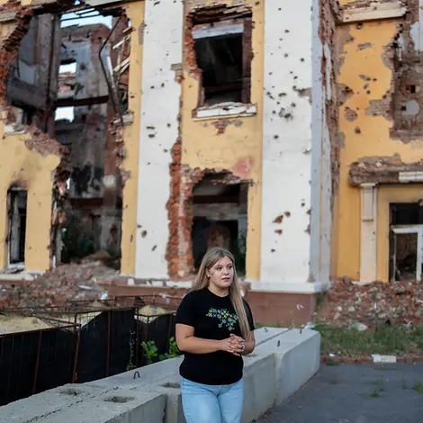 Sofia (17) steht vor einem zerstörten Schulgebäude in der Ukraine. Kinder in bewaffneten Konflikten schützen: Eine Jugendliche steht vor einem zerstörten Haus in der Ukraine.