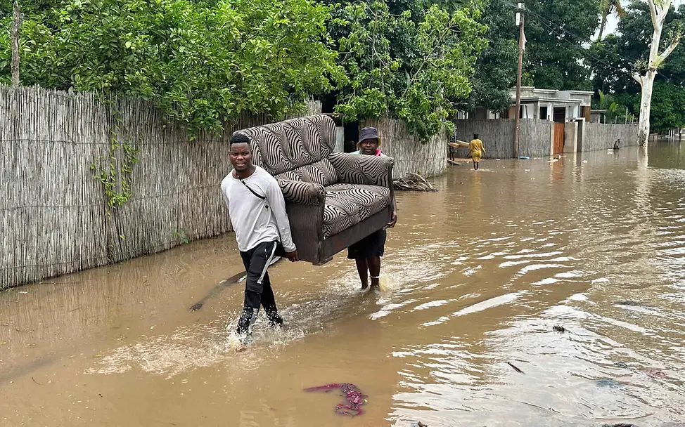 Viele Menschen verlieren als Folge von Hochwasser und Überschwemmungen ihr gesamtes Hab und Gut. | © UNICEF/Taylor Folgen von Hochwasser: Zwei Männer tragen ein Sofa eine überschwemmte Straße entlang.