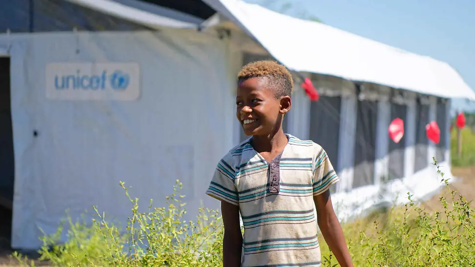 Mobile Klassenzimmer wie das Schulzelt geben Kindern die Möglichkeit, trotz Naturkatastrophen weiter zu lernen. | © UNICEF/Ramasomanana Folgen von Hochwasser: Ein Junge steht lächelnd vor einem UNICEF-Schulzelt.