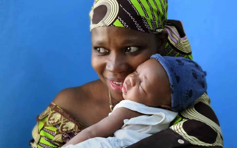 Mutter Ely hat durch das HIV-Programm trotz ihrer Erkrankung ein gesundes Kleinkind. | © UNICEF/Dejongh Eine Mutter hält ihr gesundes Baby im Arm, das dank des HIV-Programms von der Krankheit ihrer Mutter verschont bleibt.
