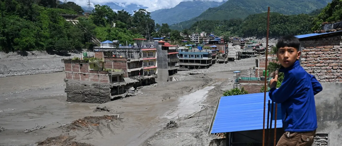 Ein Kind steht vor Häusern, die durch die Sturzflut in Nepal beschädigt wurden. | ARUN SANKAR / AFP Sturzflut Nepal: Ein Kind steht vor beschädigten Häusern