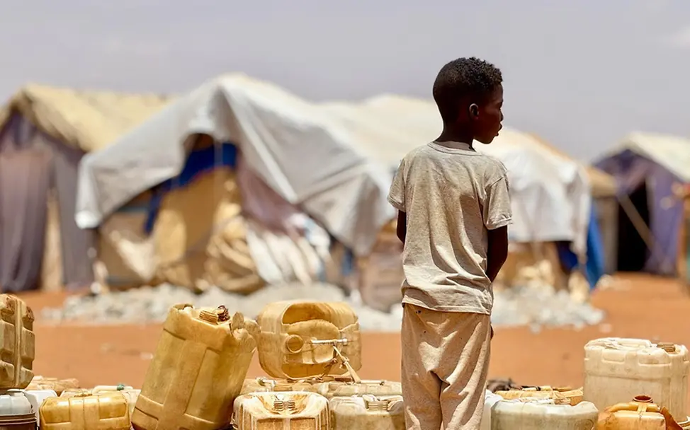 Ein Junge wartet auf Wasser in einer Unterkunft für Vertriebene in Al-Obeid. | © UNICEF/UNICEF Ein Junge wartet auf Wasser in einer Unterkunft für Vertriebene in Al-Obeid.