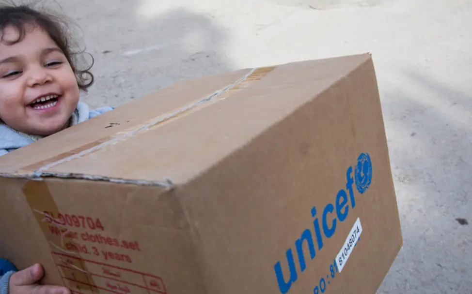 Ein Mädchen trägt ein Paket mit Winterkleidung | © UNICEF/Penttila Syrien: Ein Mädchen trägt ein Paket
