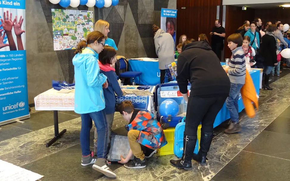 Kinder entdecken die UNICEF-Schule in der Kiste|©UNICEF/Günter Fuchs Junge Fans von Willi Weitzel am UNICEF-Stand in Nürnberg
