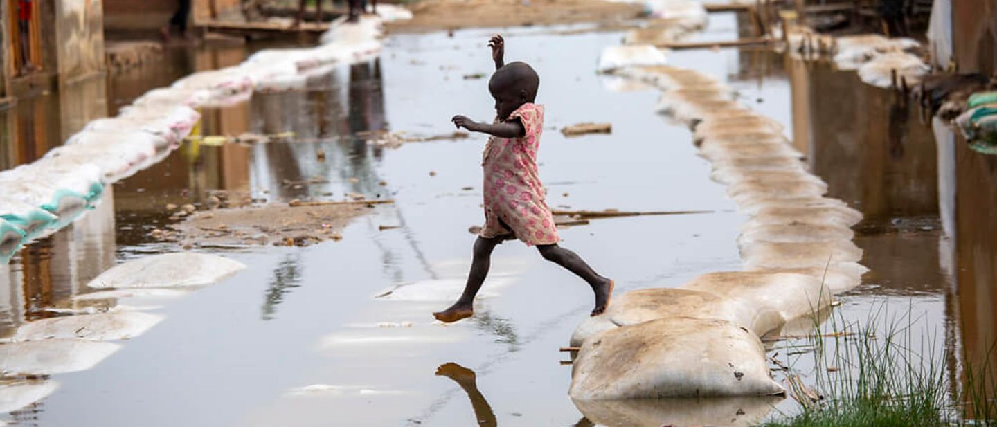 Burundi: Ein Mädchen geht über einen Steg aus Sandsäcken.