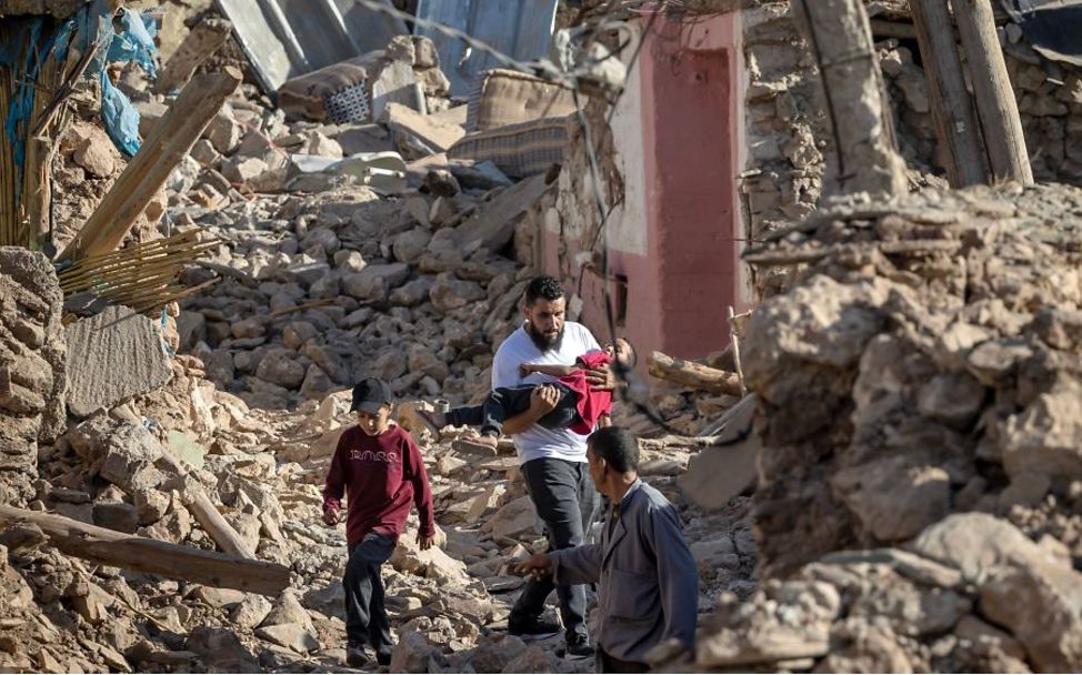 Marokko: Ein Mann trägt einen Jungen durch Trümmerberge.
